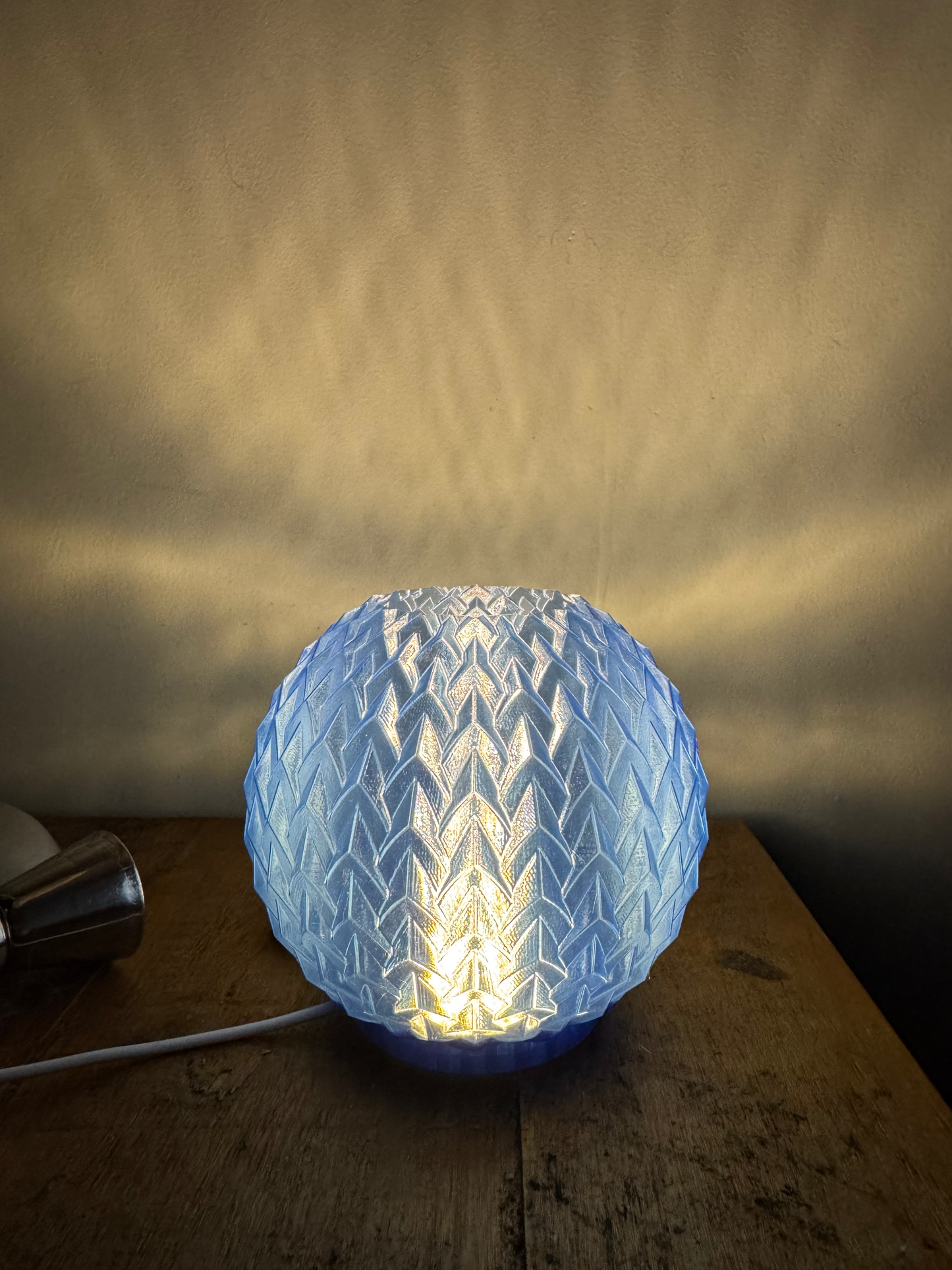 Spherical blue light fixture casting a shadow on a wooden surface